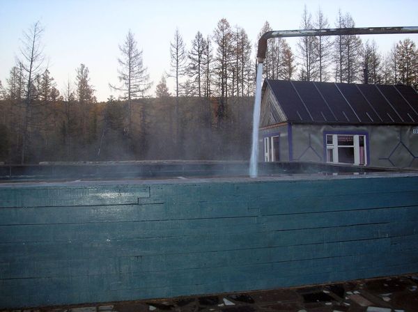 Нахот база отдыха бассейн струя горячей воды из горячего источника деревянный дощатый бассейн домик за бассейном голубые доски покрашены голубым цветом
